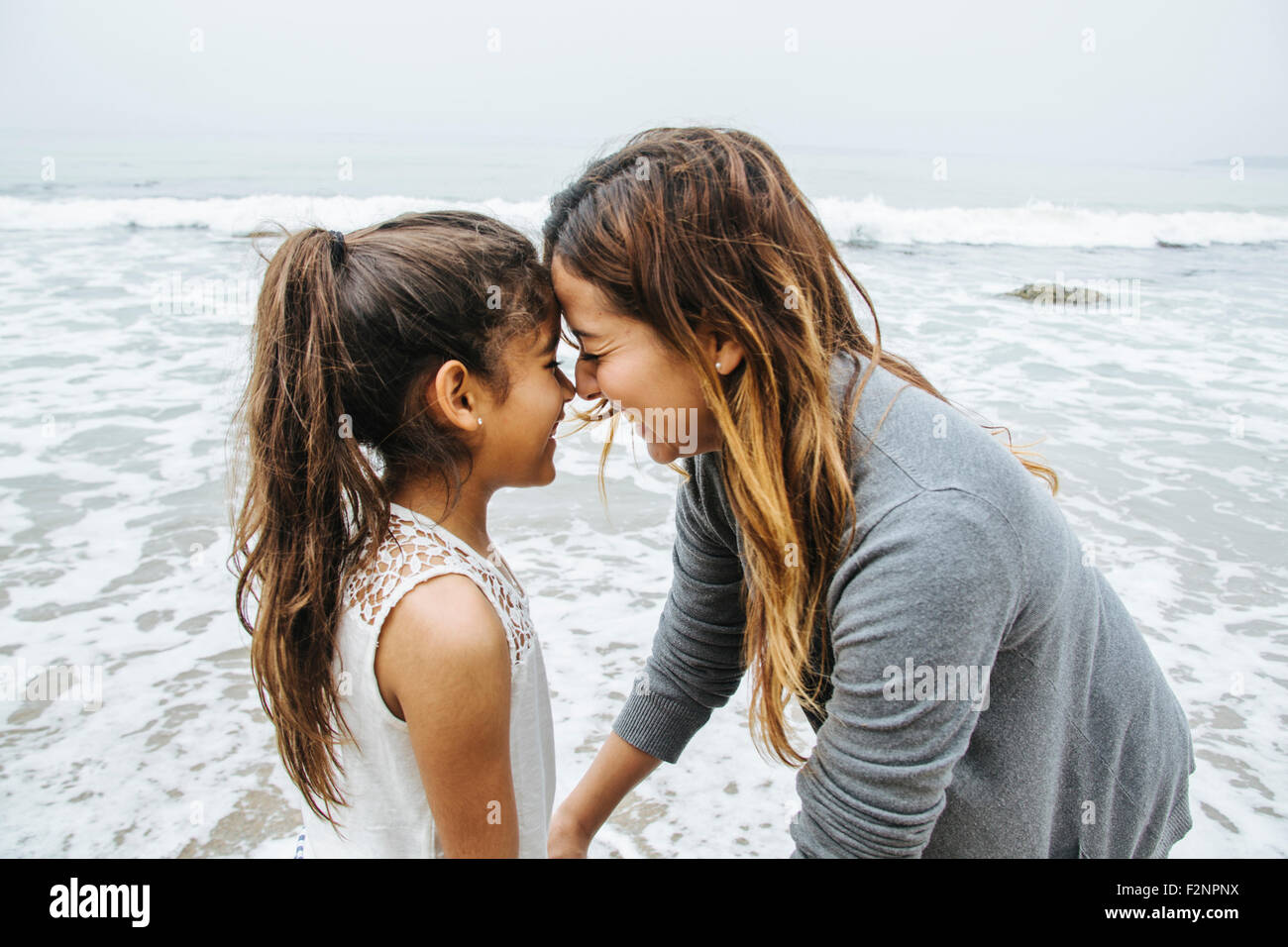 Hispanic mother and daughter standing on beach Stock Photo
