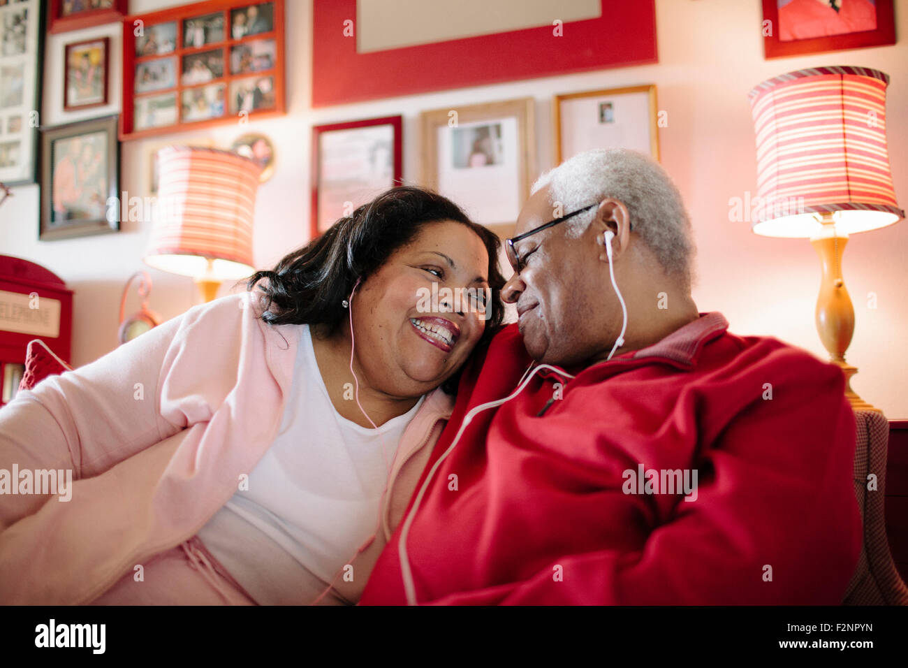 Couple listening to earbuds in living room Stock Photo