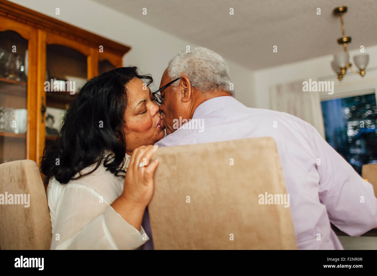Close up of kissing couple in dining room Stock Photo