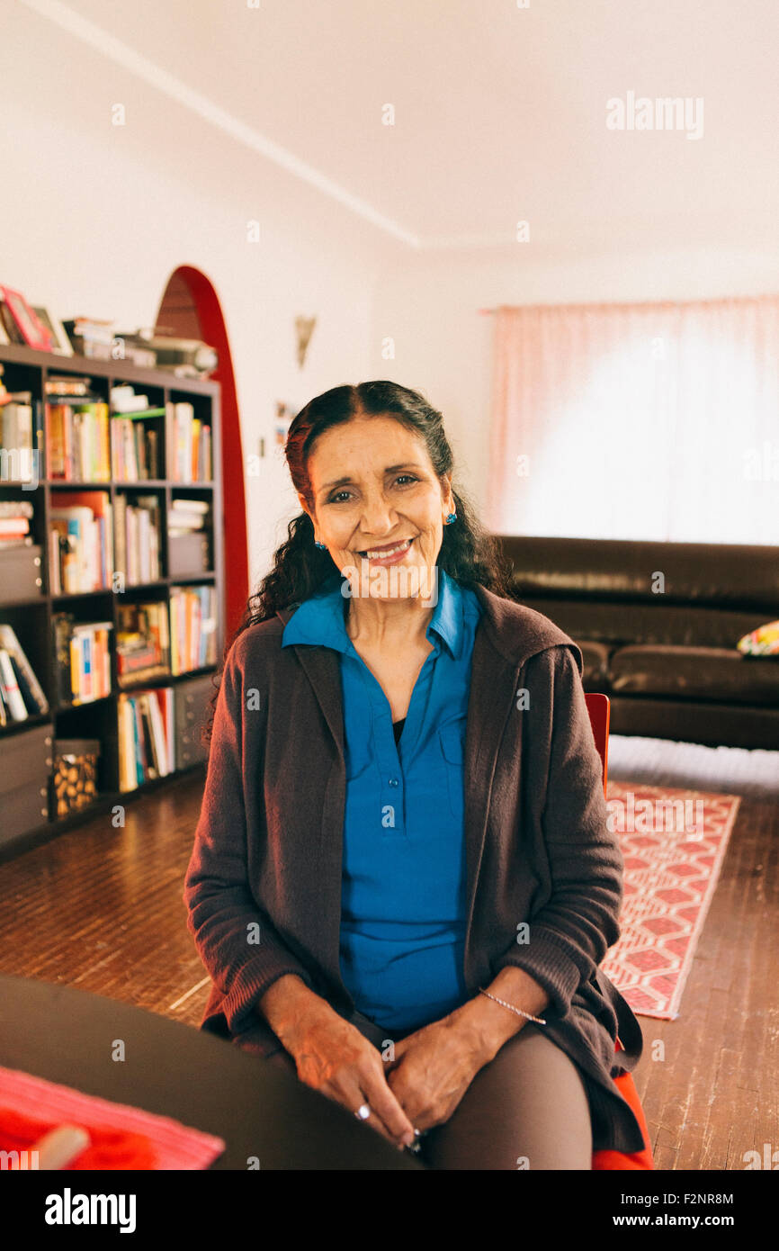 Hispanic woman smiling in living room Stock Photo
