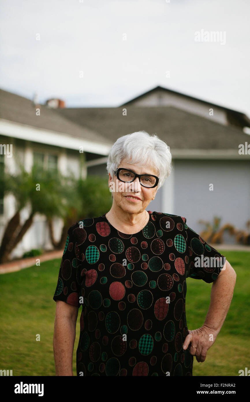 Older woman standing with hands on hips in backyard Stock Photo