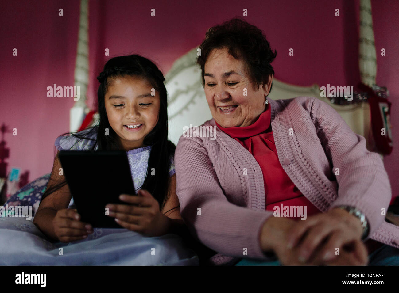 Hispanic grandmother and granddaughter using digital tablet on bed Stock Photo