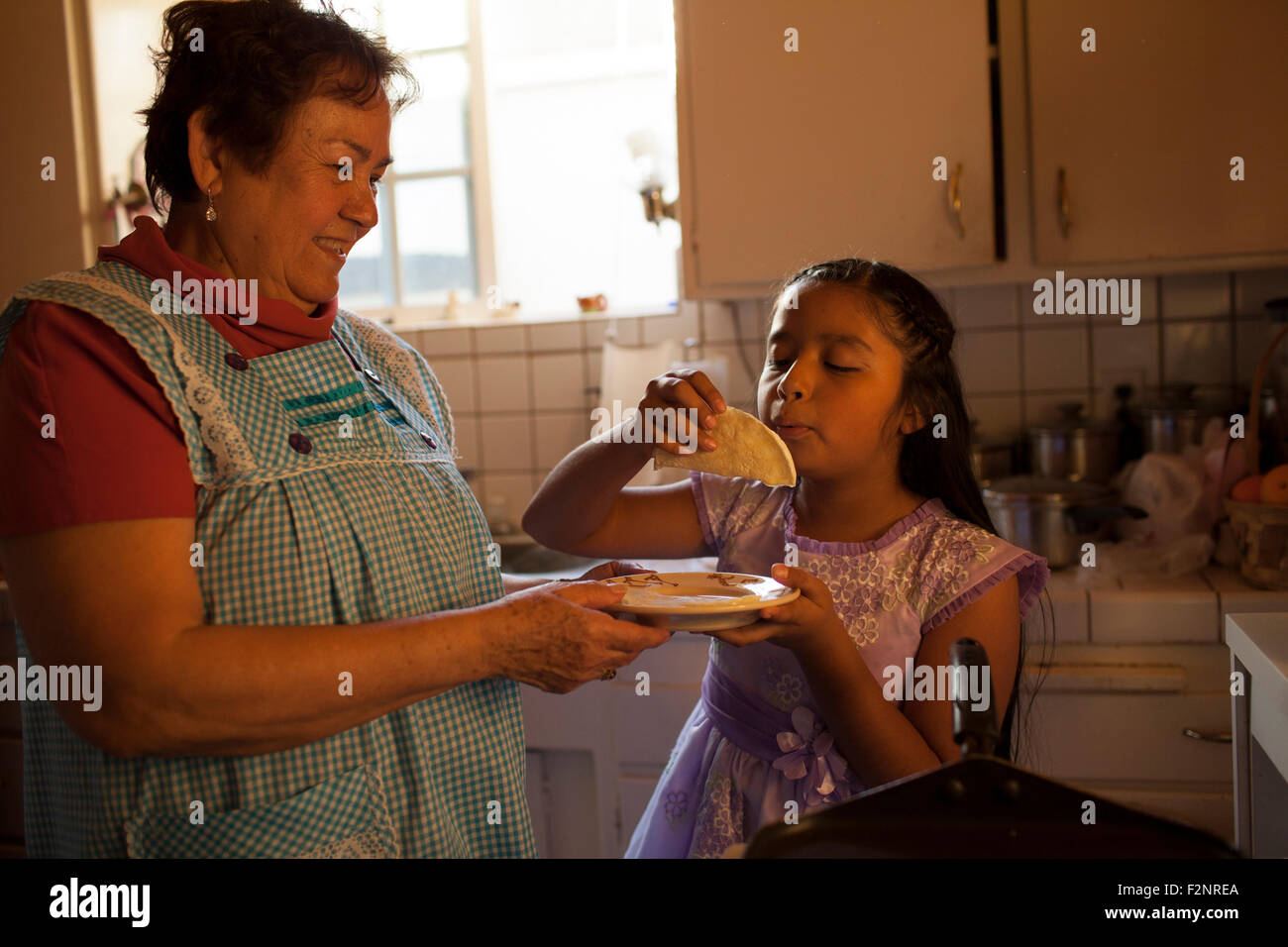 Hispanic woman cooking for granddaughter in kitchen Stock Photo