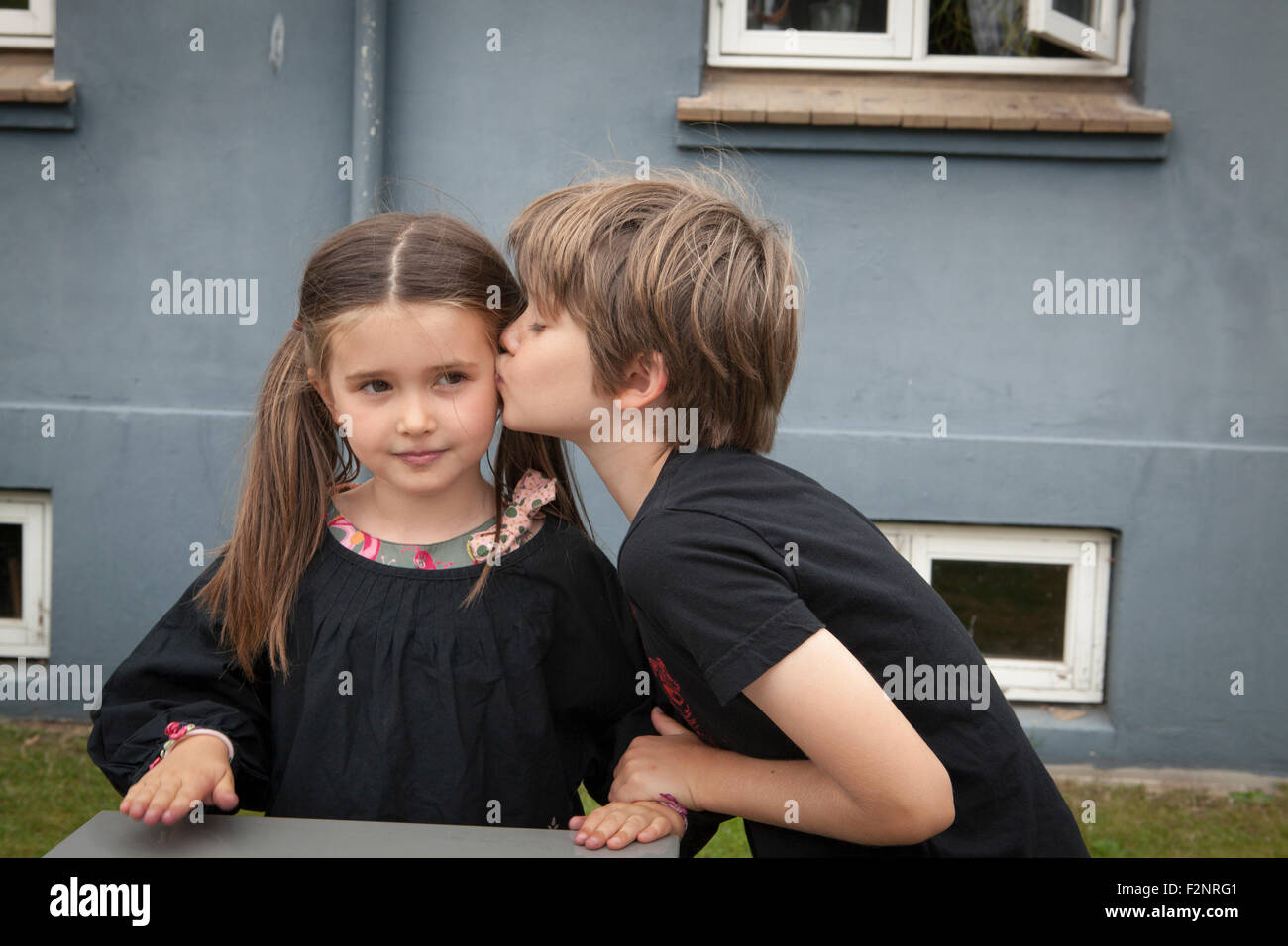 Caucasian boy kissing sister in backyard Stock Photo