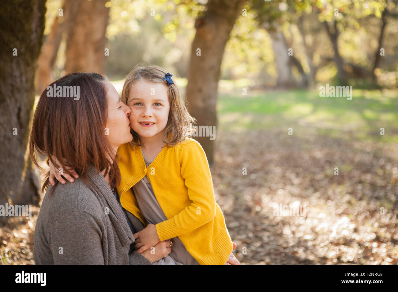 Mother kissing daughter in park Stock Photo