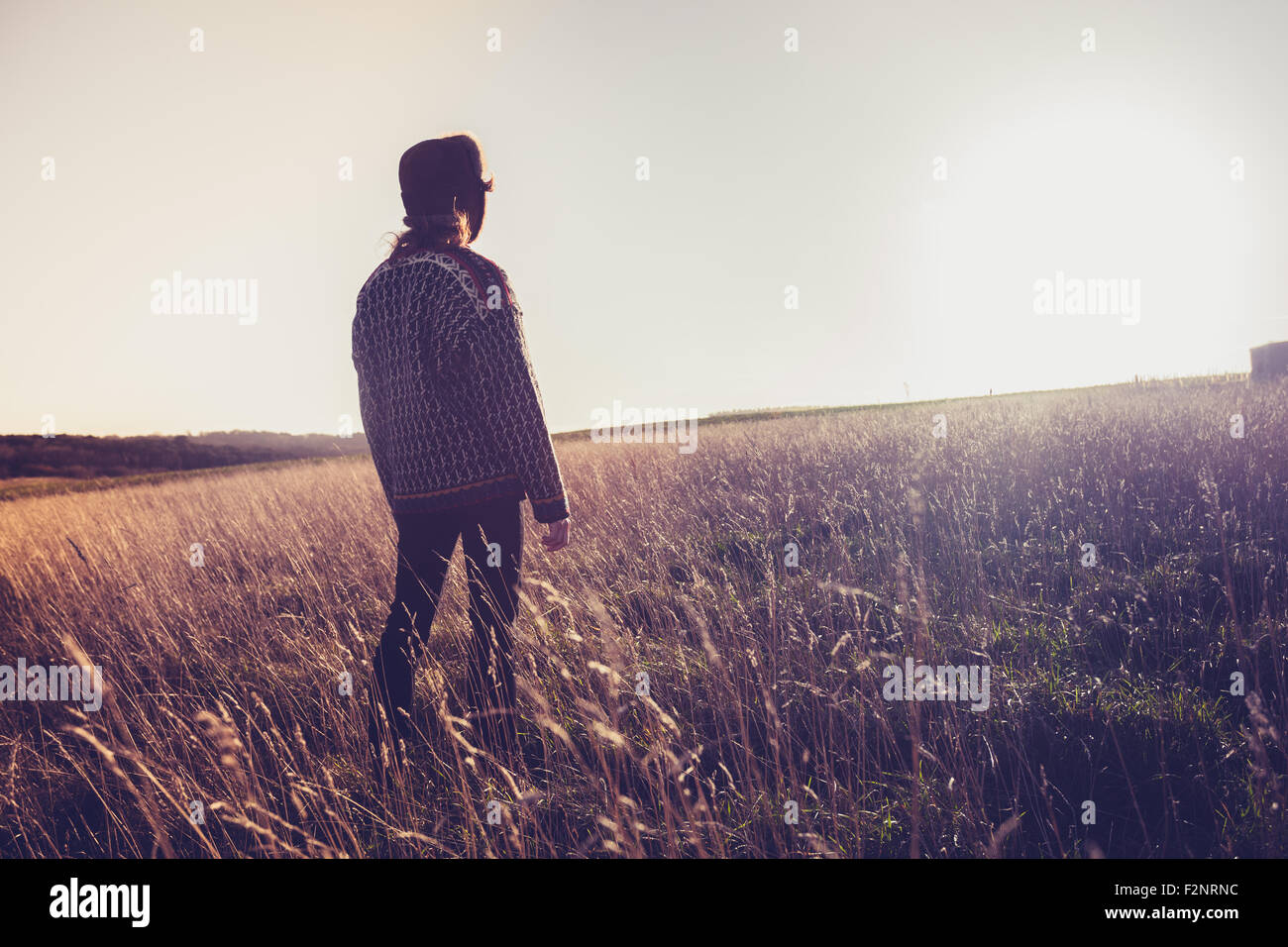Woman standing in field at sunset Stock Photo - Alamy