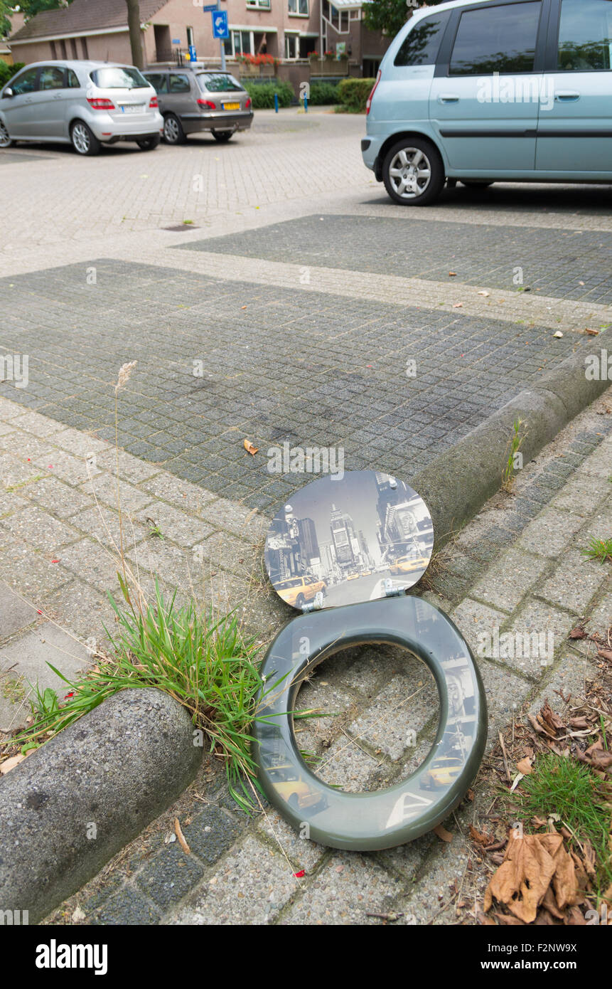 ALMELO, NETHERLANDS - AUGUST 8, 2015: Broken toilet seat with new york print on it left on the street Stock Photo