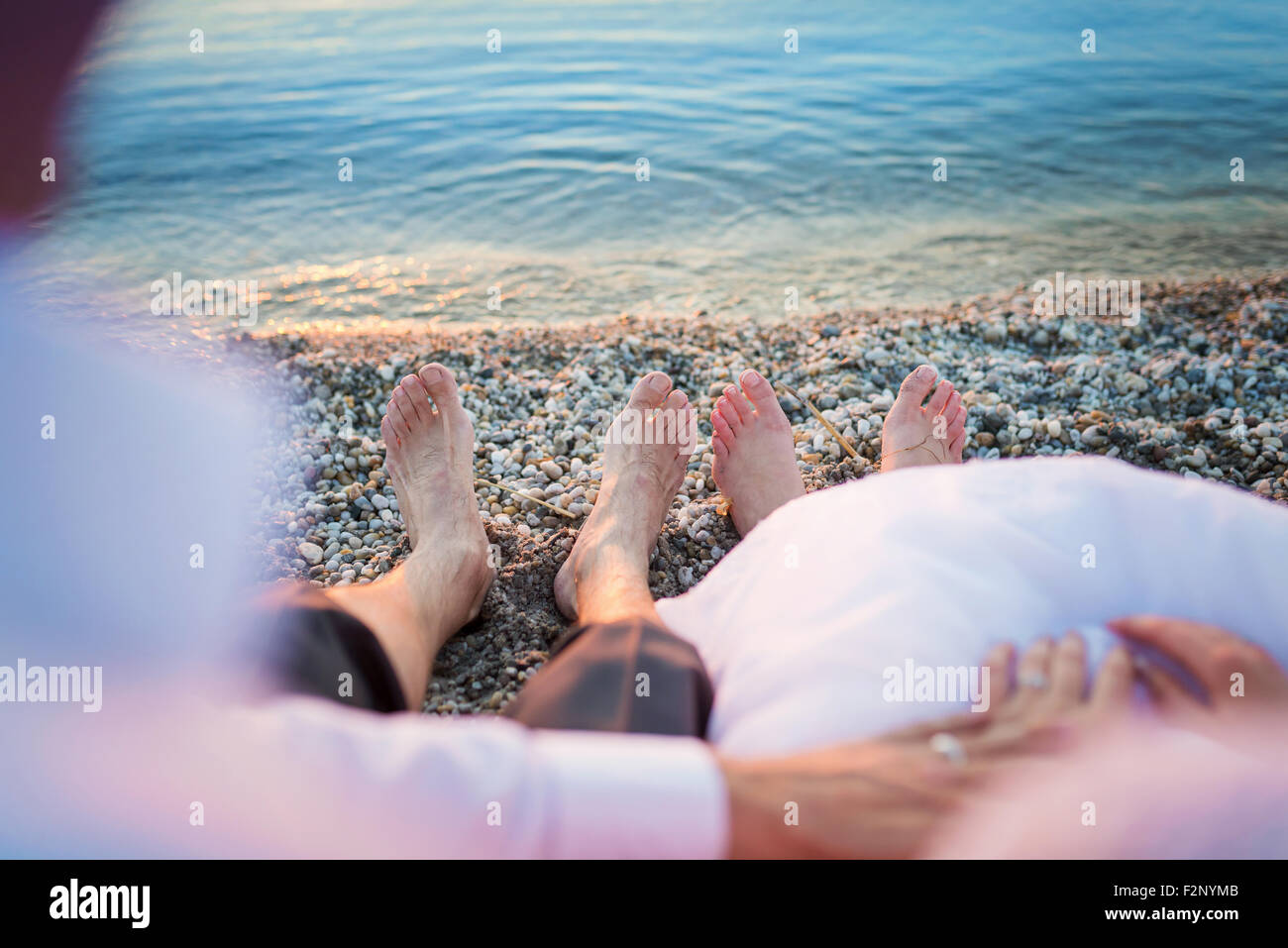 Feet of a bride and groom sitting on a beach Stock Photo