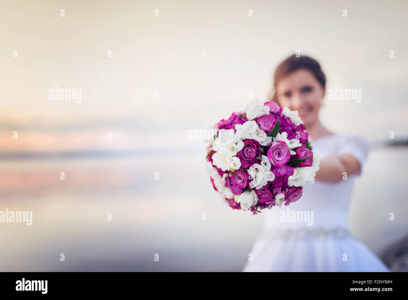 Beautiful bride with bouquet standing on the beach Stock Photo