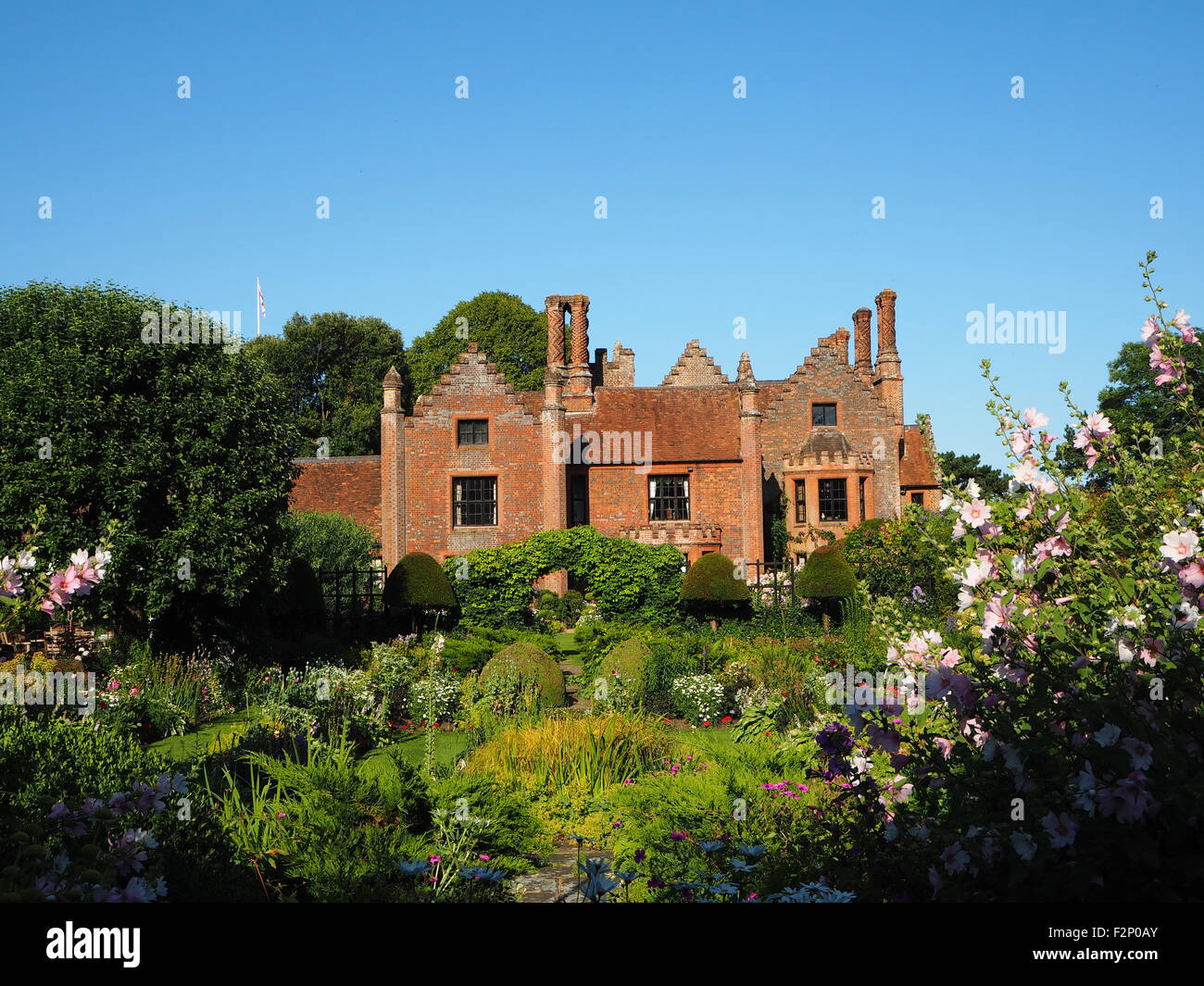 Chenies Manor House and sunken garden with beautiful perennial flower borders and fresh green foliage;sunny with blue sky. Stock Photo
