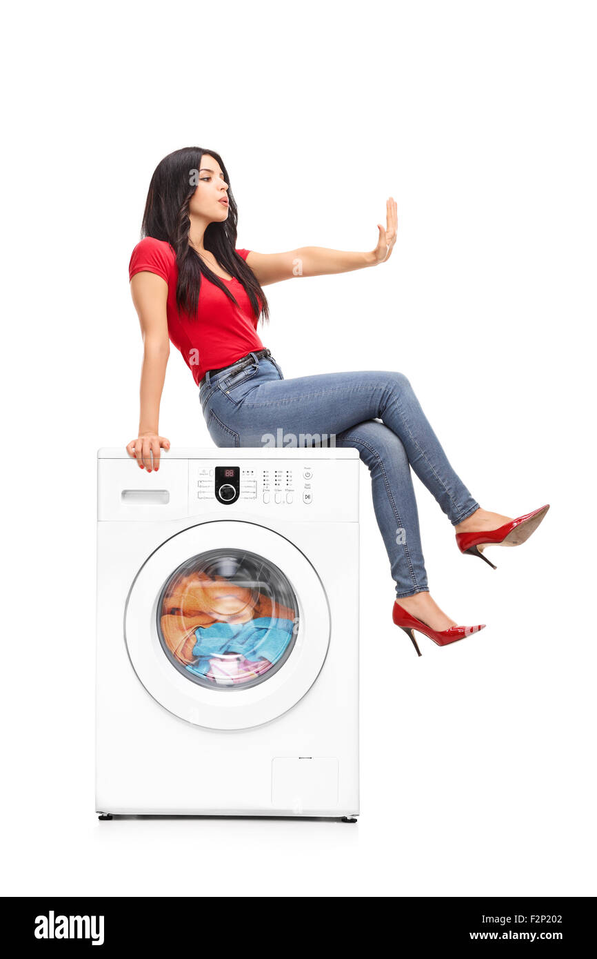 Vertical shot of a young woman waiting for the washing machine to finish the laundry and meanwhile looking at her fingernails Stock Photo