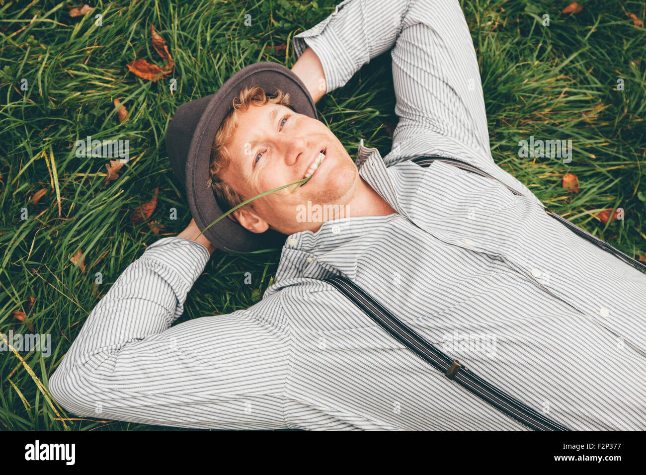 https://c8.alamy.com/comp/F2P377/portrait-of-smiling-young-man-lying-on-a-meadow-with-hands-behind-F2P377.jpg