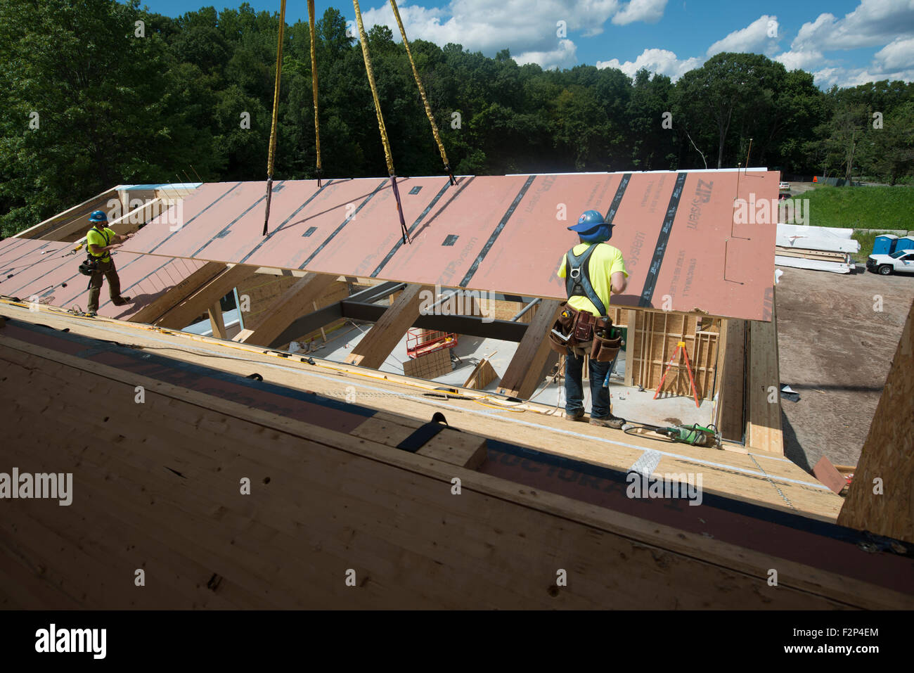 Construction workers install roof panels on Leed Platinum Common Ground
