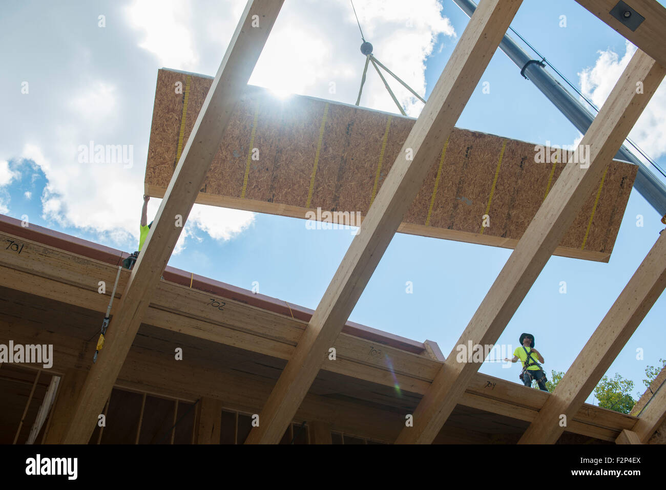 Construction workers install roof panels on Leed Platinum Common Ground High School building. Stock Photo