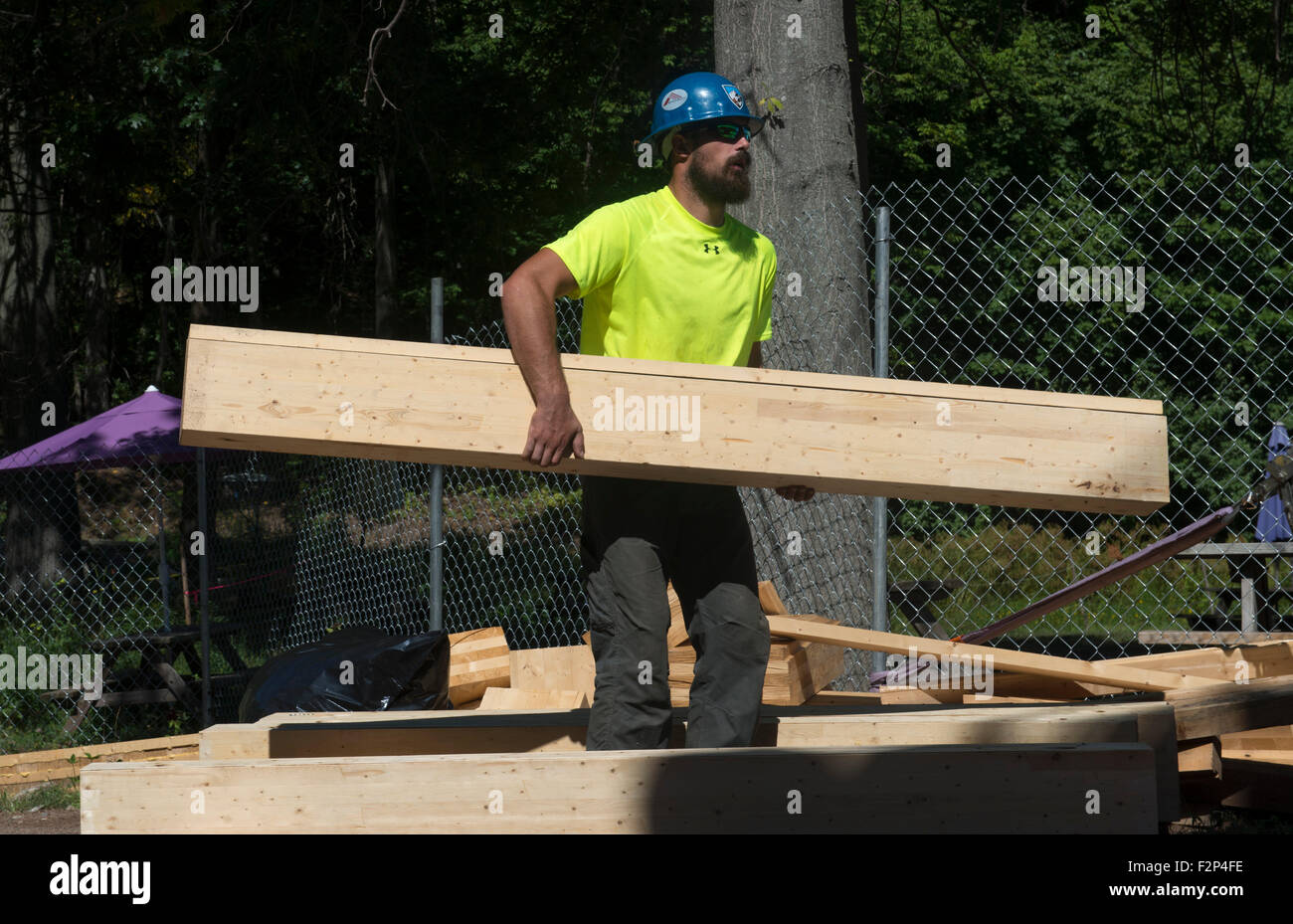Construction worker carries beam for new Common Ground HIgh School building. Stock Photo