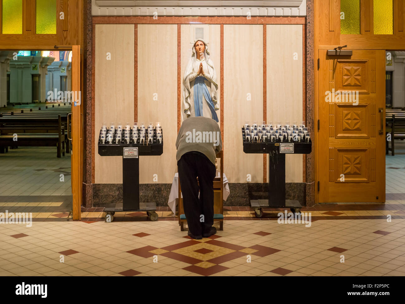 Old man prostating before virgin Mary statue, in Basilica of Sainte-Anne-de-Beaupré in Quebec, Canada. Stock Photo