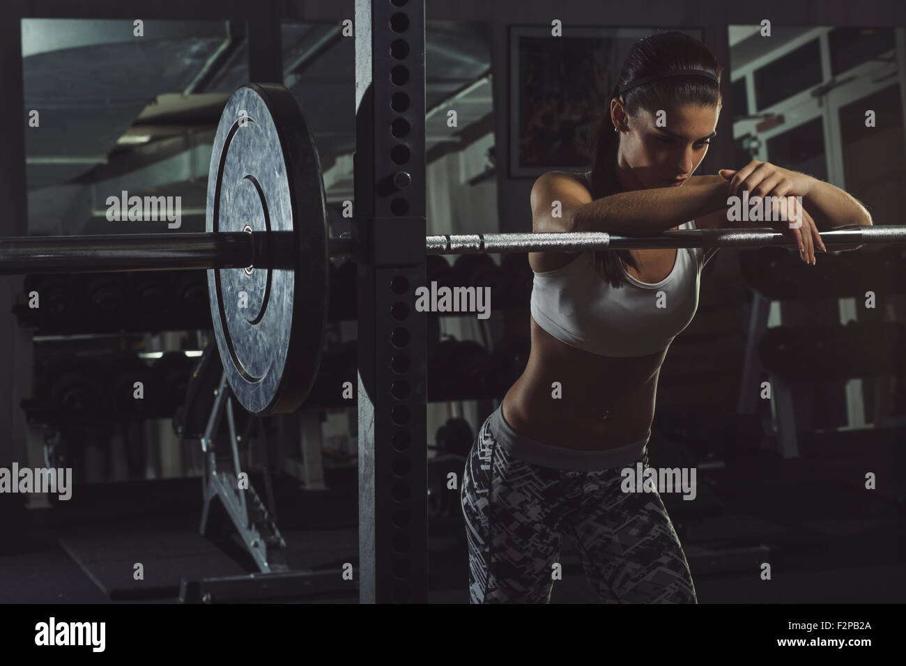 Muscular athlete leaning on barbell in gym Stock Photo
