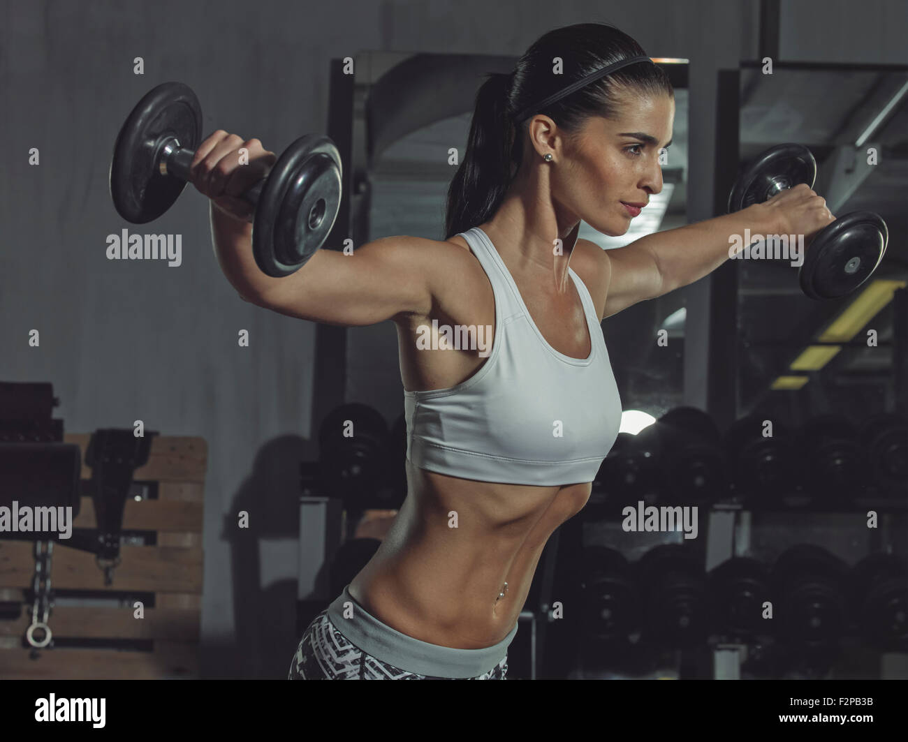 Portrait of a female athlete training with dumbbells in gym Stock Photo
