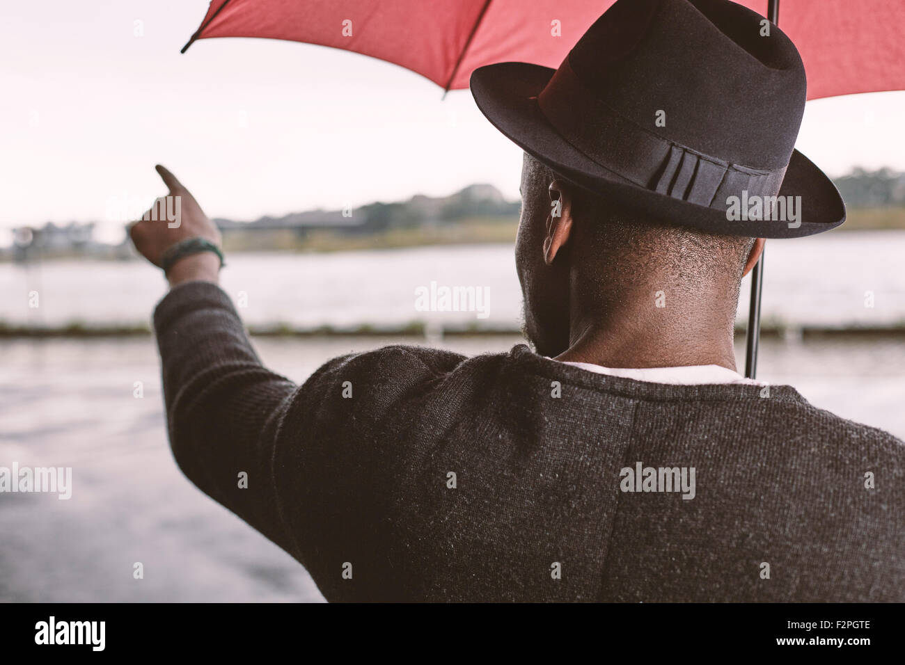 Young man with umbrella pointing his finger Stock Photo Alamy