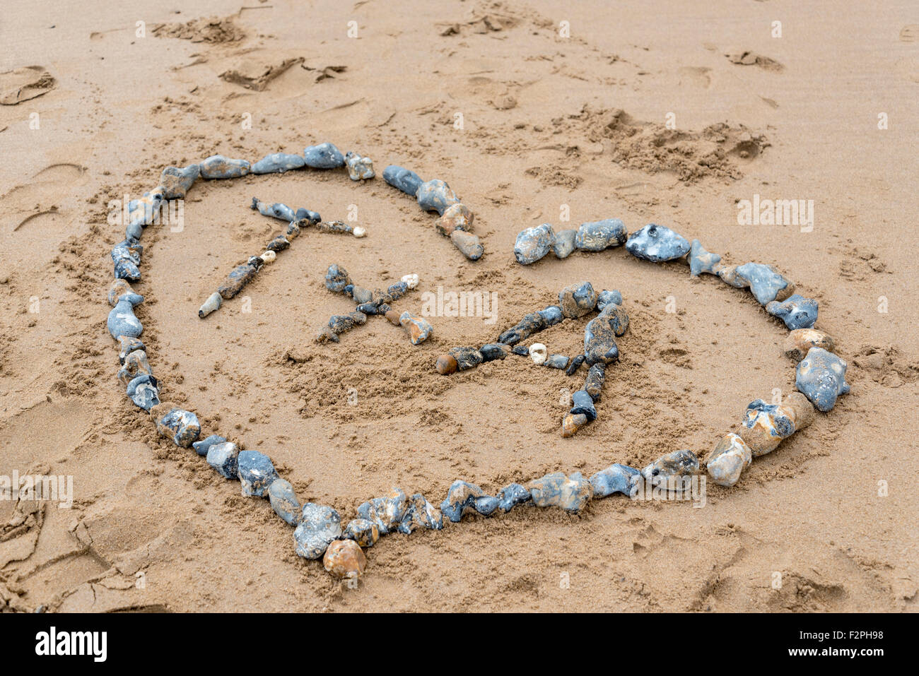 The letters T and A enclosed in a pebble heart on the sandy beach at Ramsgate, Kent Stock Photo