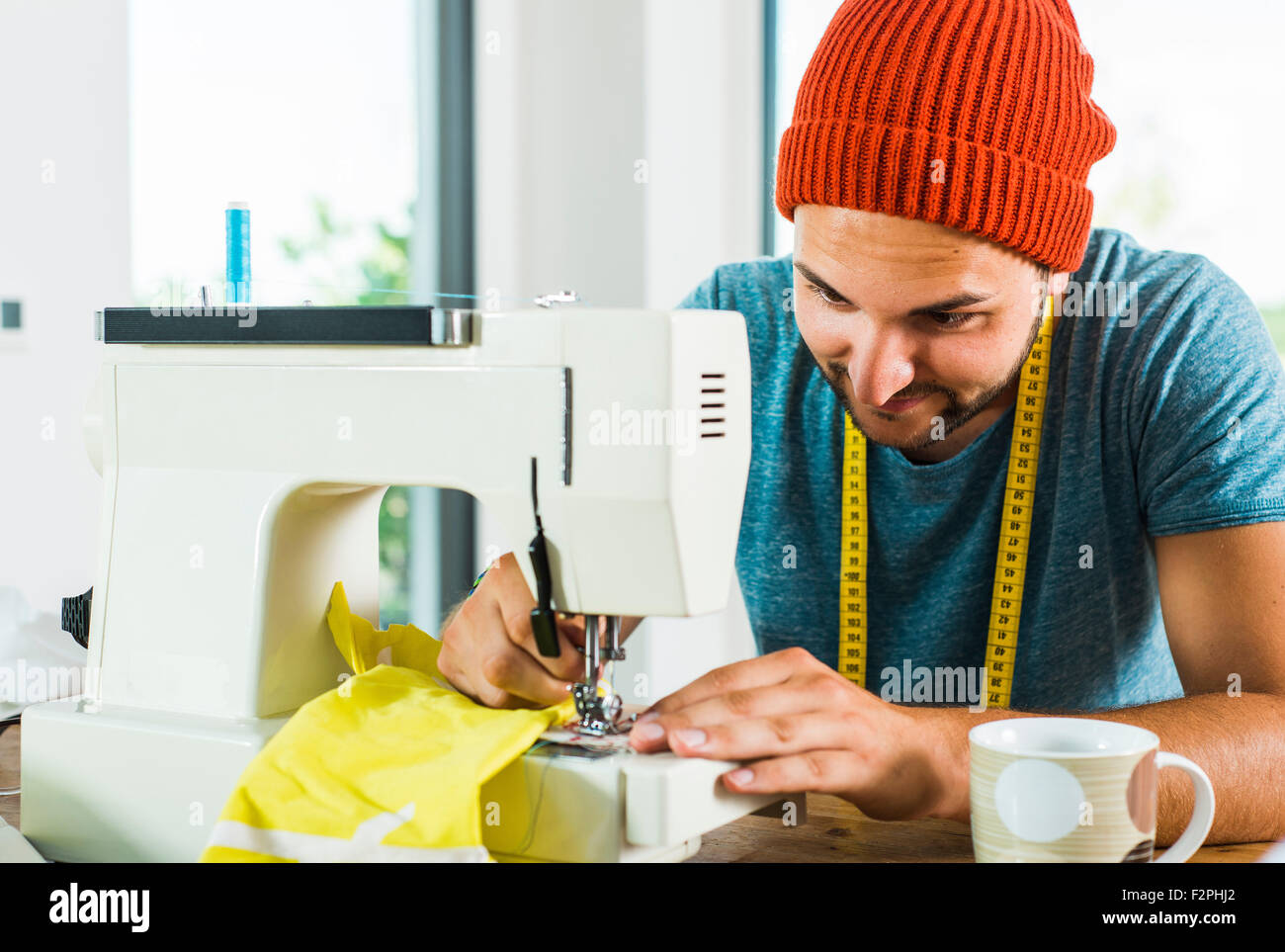 Young man at home using sewing machine Stock Photo - Alamy