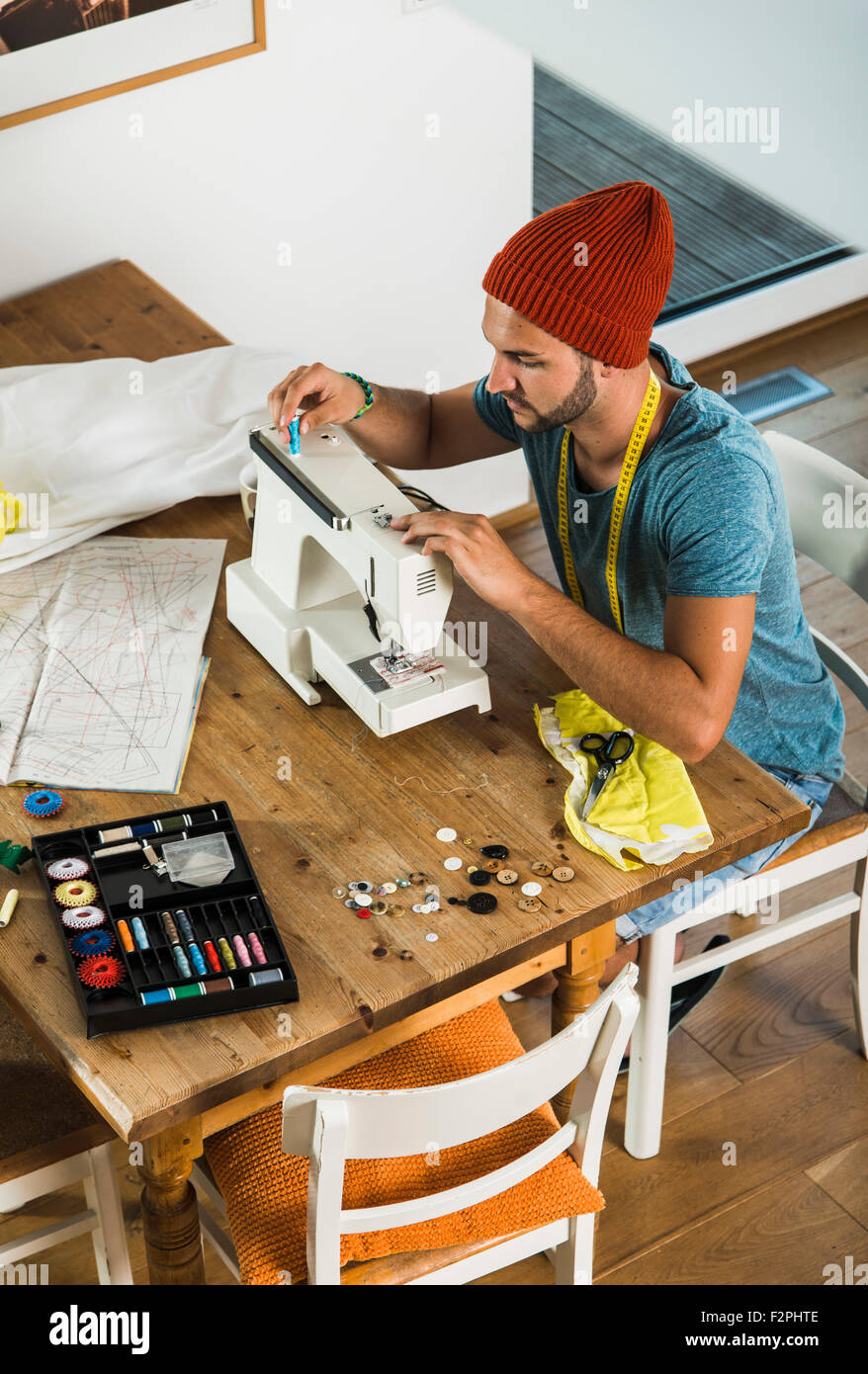Young man at home using sewing machine Stock Photo - Alamy