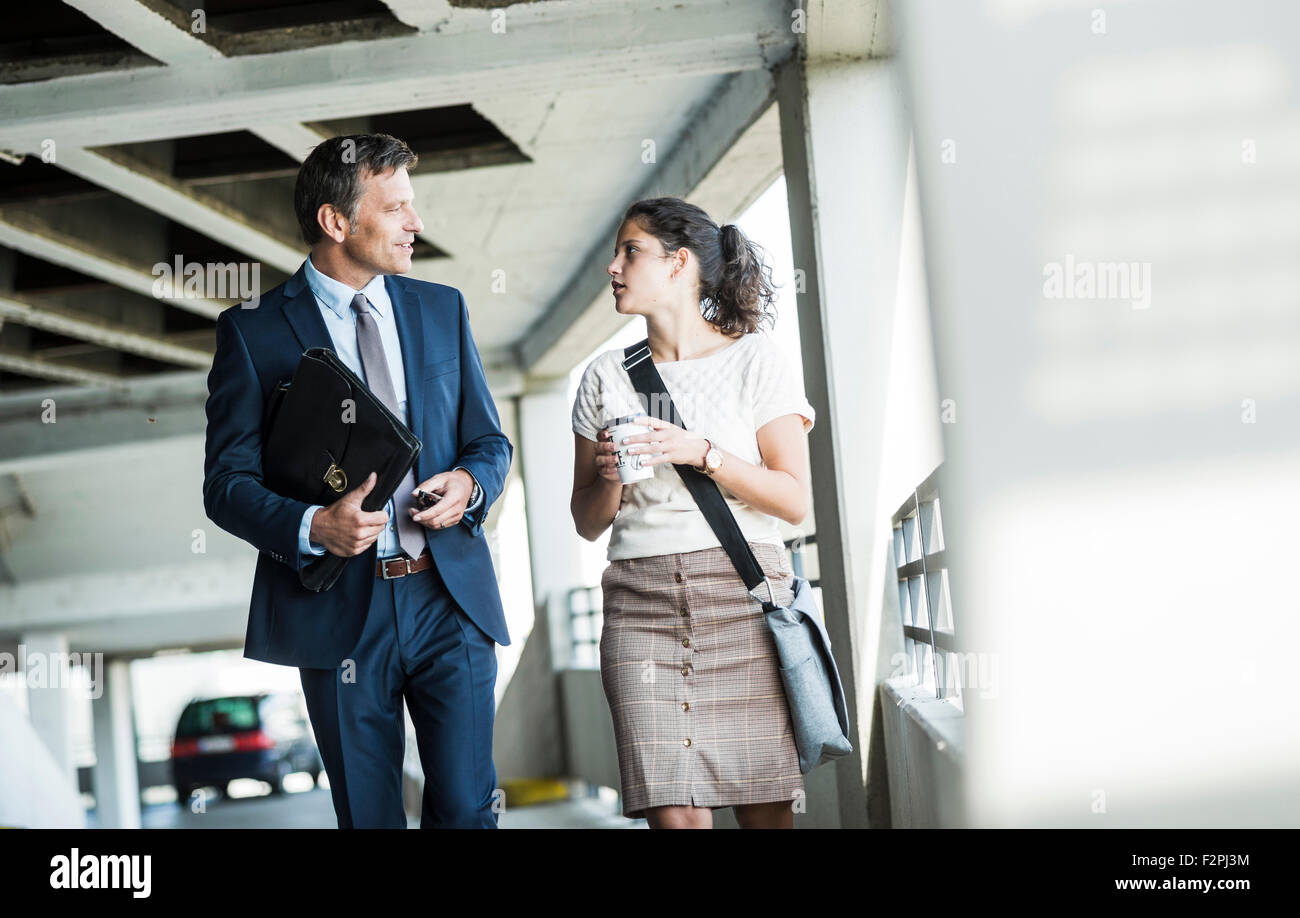 Mature businessman and young colleague walking in parking garage, talking Stock Photo