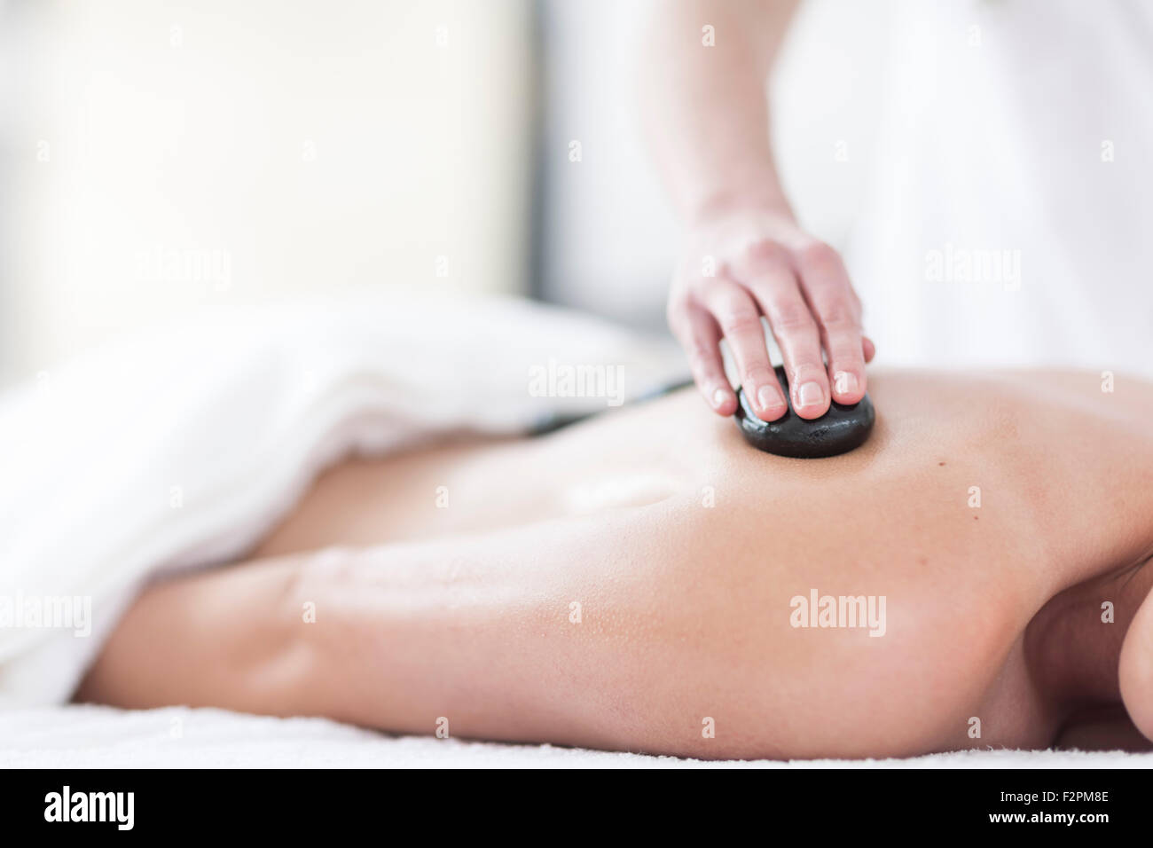 Woman receiving hot stone massage in a spa Stock Photo