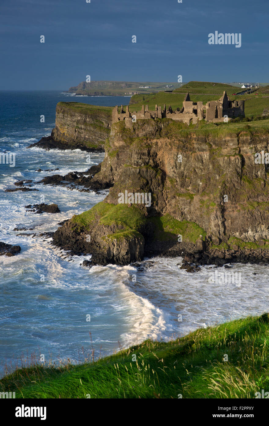 Evening sunlight over the ruins of Dunluce Castle and the cliffs of County Antrim, Northern Ireland, UK Stock Photo