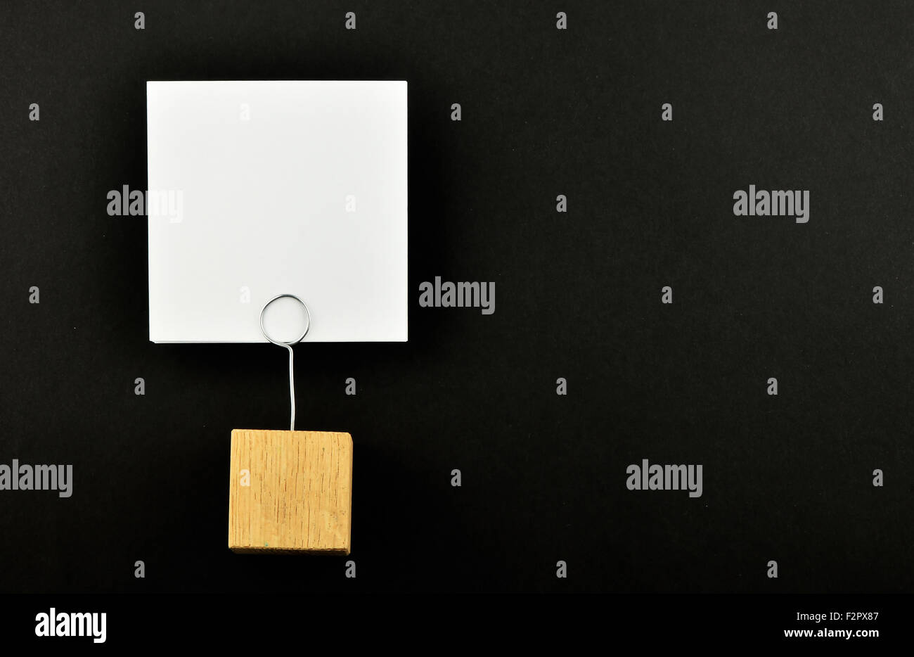 One white paper note with wooden holder isolated at black paper ...