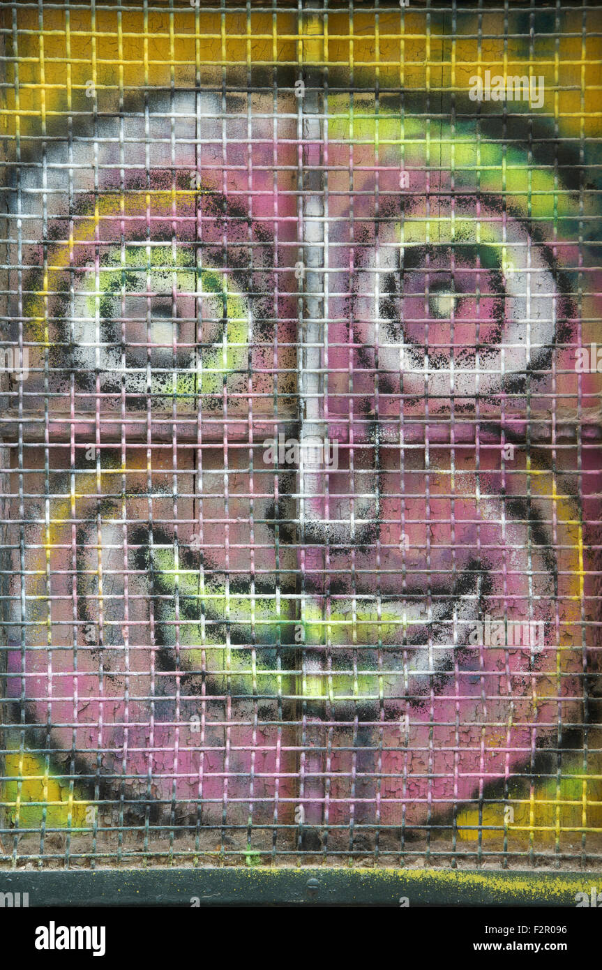 Ugly pink face. Colourful graffiti spray painted on a window shutter. Detail of urban street art by artist known as Loko. Montpellier, South of France. Stock Photo