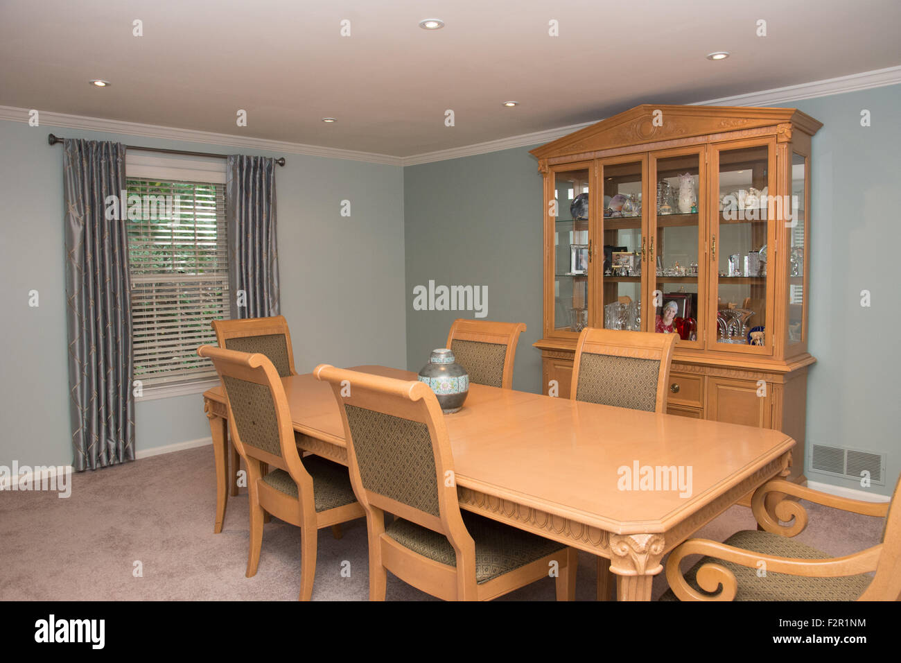 Dining room interior with a large wooden table, chairs, and china cabinet. Stock Photo