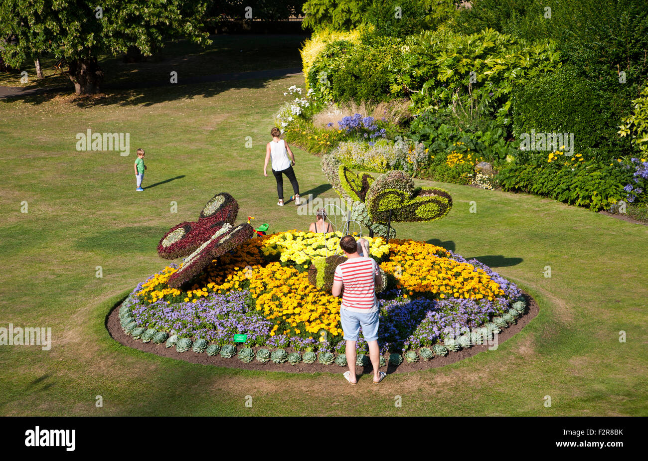Family enjoying floral display of butterflies in Parade Gardens public park in city centre of