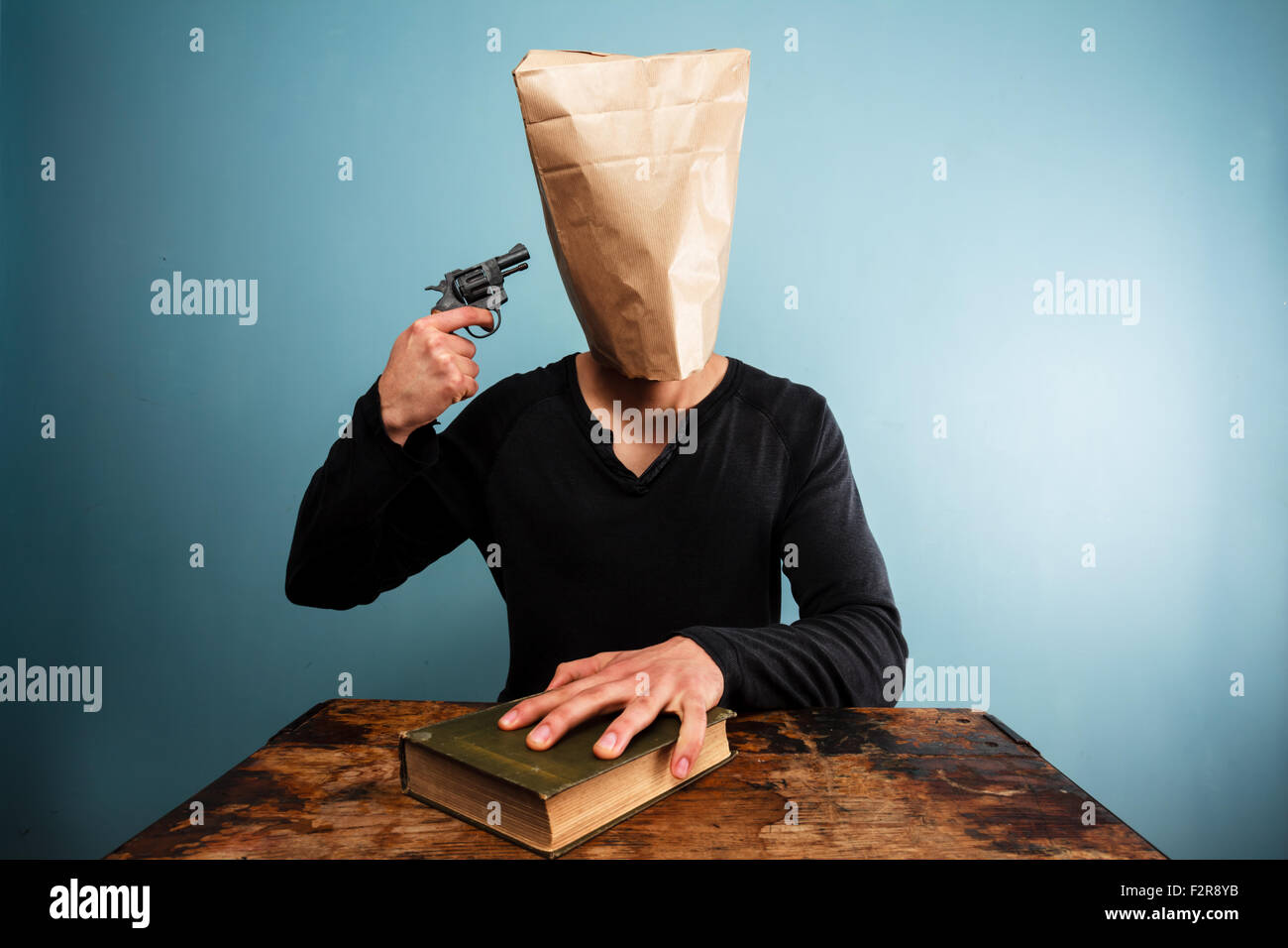 Man With Hand On Bible And Bag Over Head Committing Suicide Stock Photo man-with-hand-on-bible-and-bag-over-head-committing-suicide-stock-photo