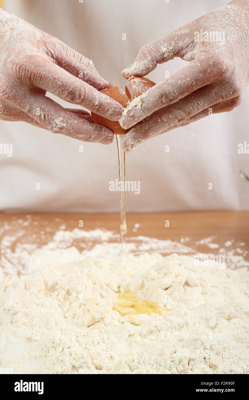 A baker cracking an egg into a pile of flour. Making Pastry Dough for