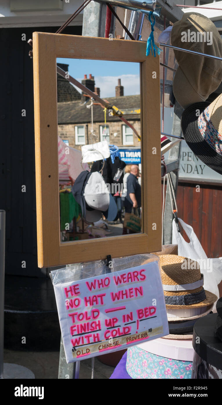 Humorous sign on market stall 'He Who Wears No Hat When Told Finish Up In Bed With Cold'  Otley, Yorkshire, England, UK Stock Photo