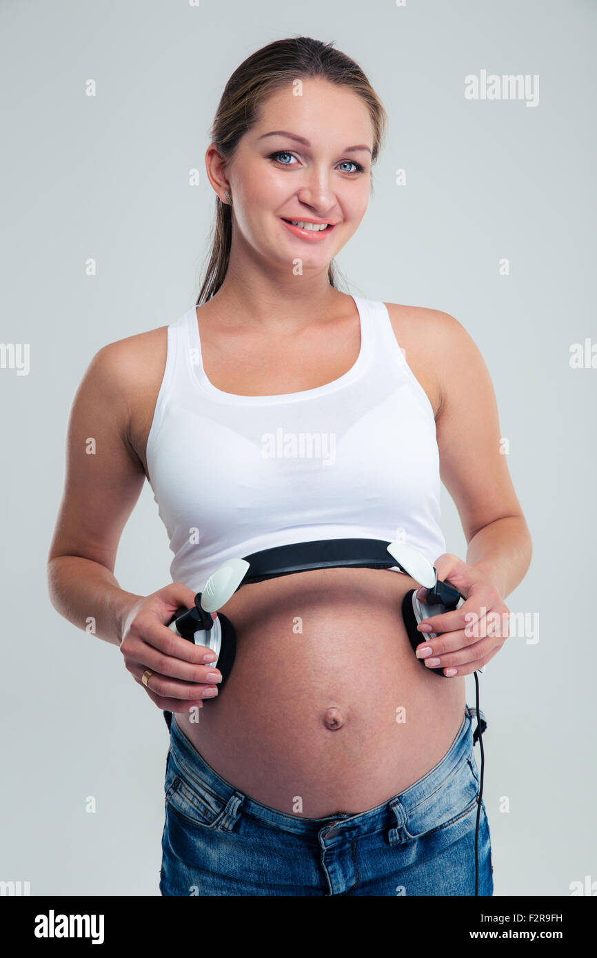 happy pregnant woman holding headphones on her belly at home. Pregnancy,  people, technology concept Stock Photo - Alamy
