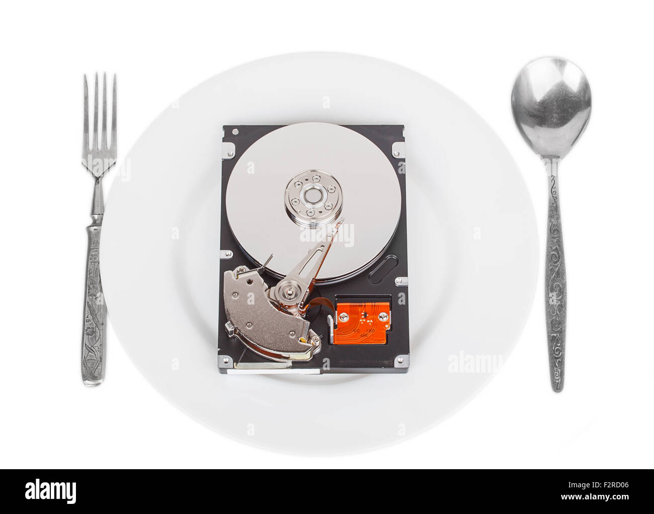 opened hard drive disk on a white plate with a fork and spoon isolated on the white background Stock Photo