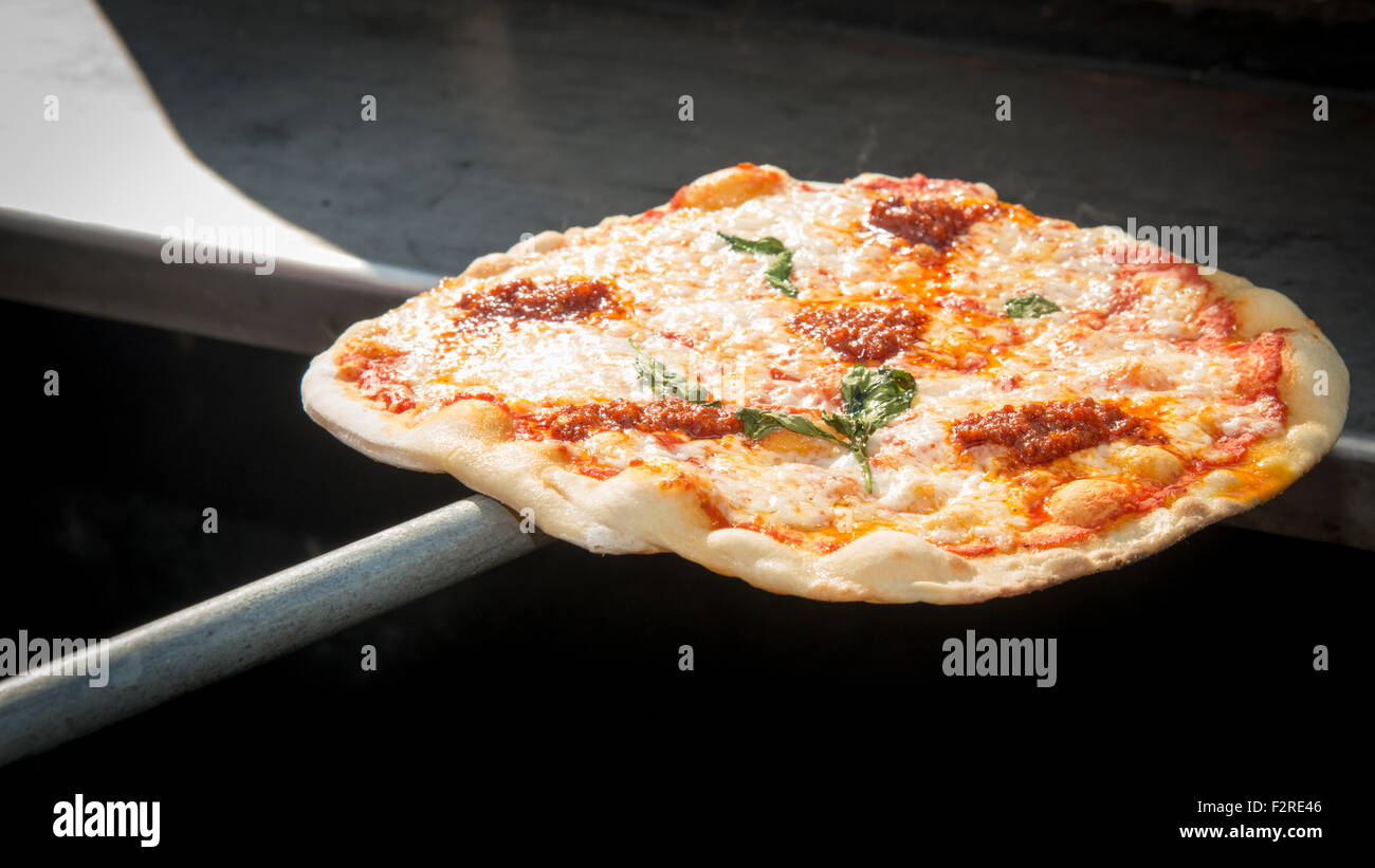 A freshly cooked pizza just removed from an oven on a pizza paddle Stock Photo