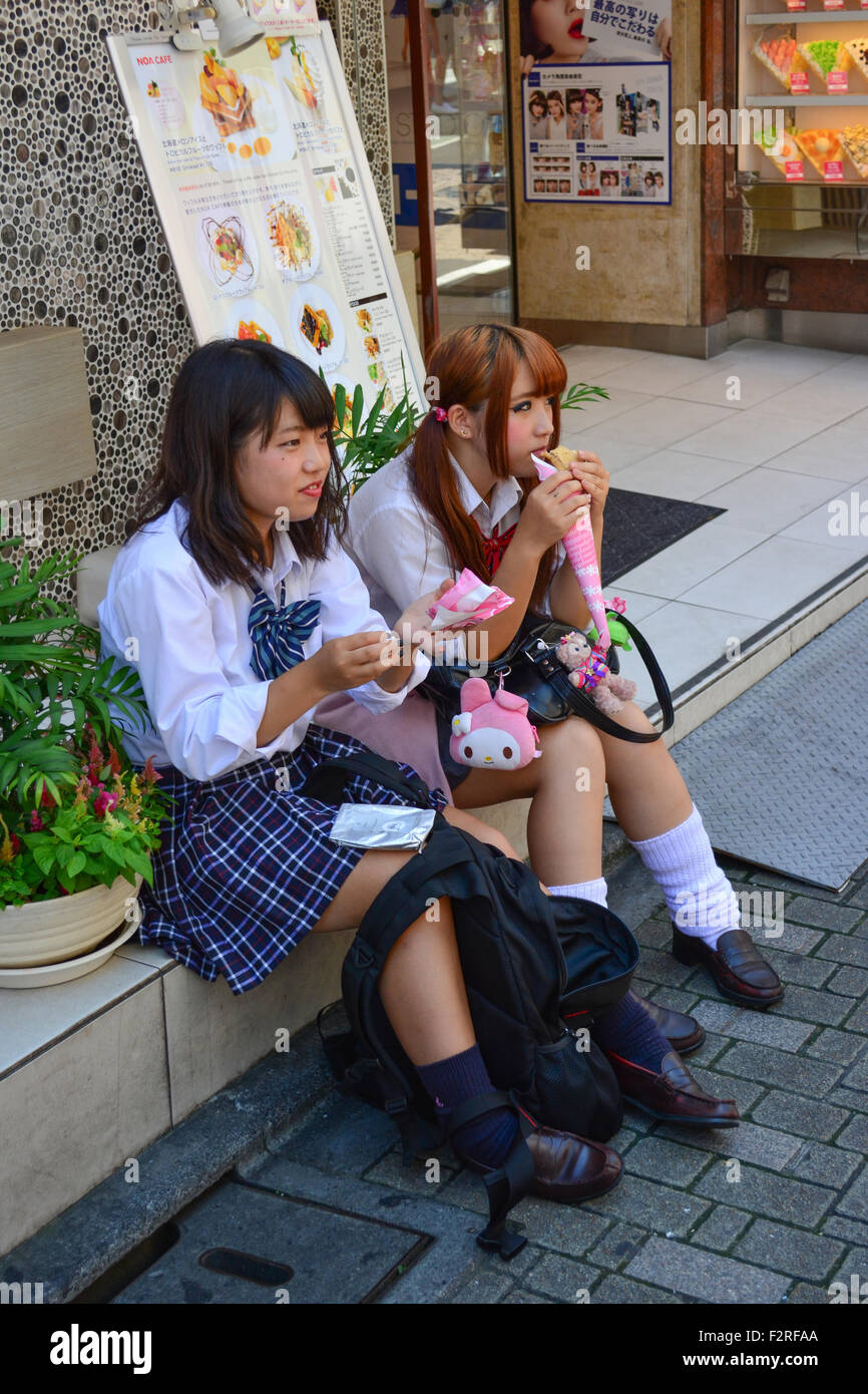 Two schoolgirls having a bite. Harajuku, Tokyo. Stock Photo