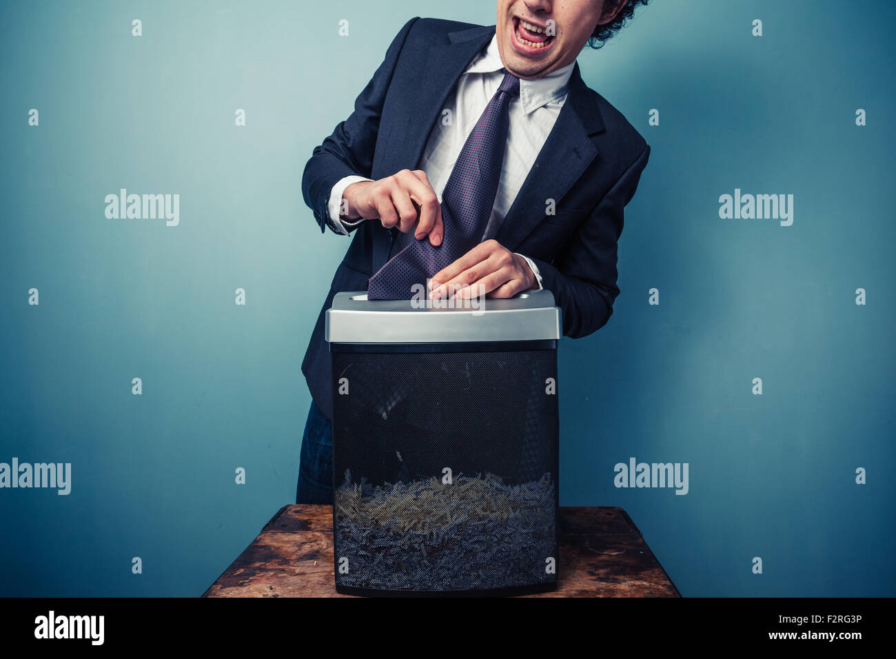 Clumsy businessman with his tie stuck in a paper shredder Stock Photo
