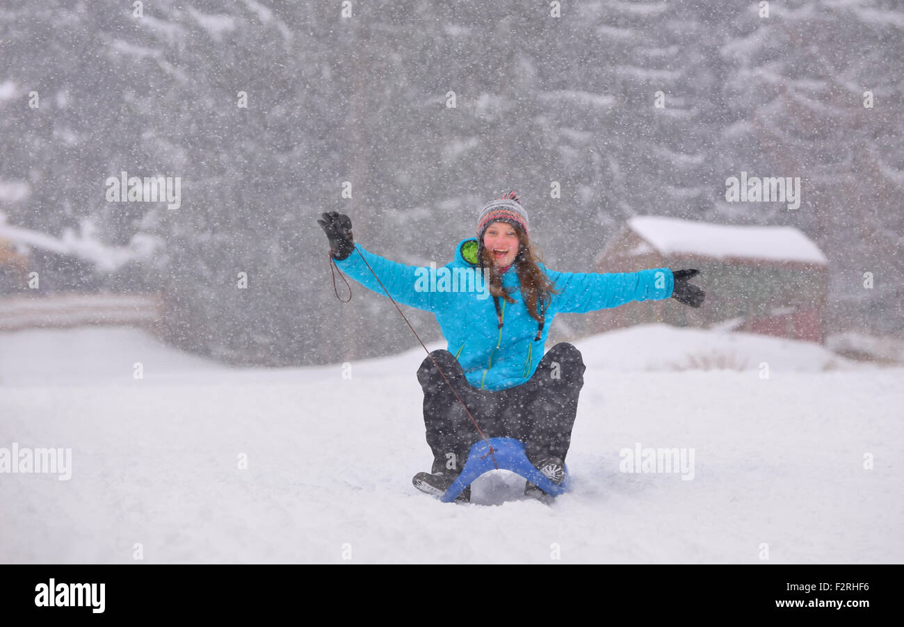 Teen girl on sledge in snowy winter forest Stock Photo