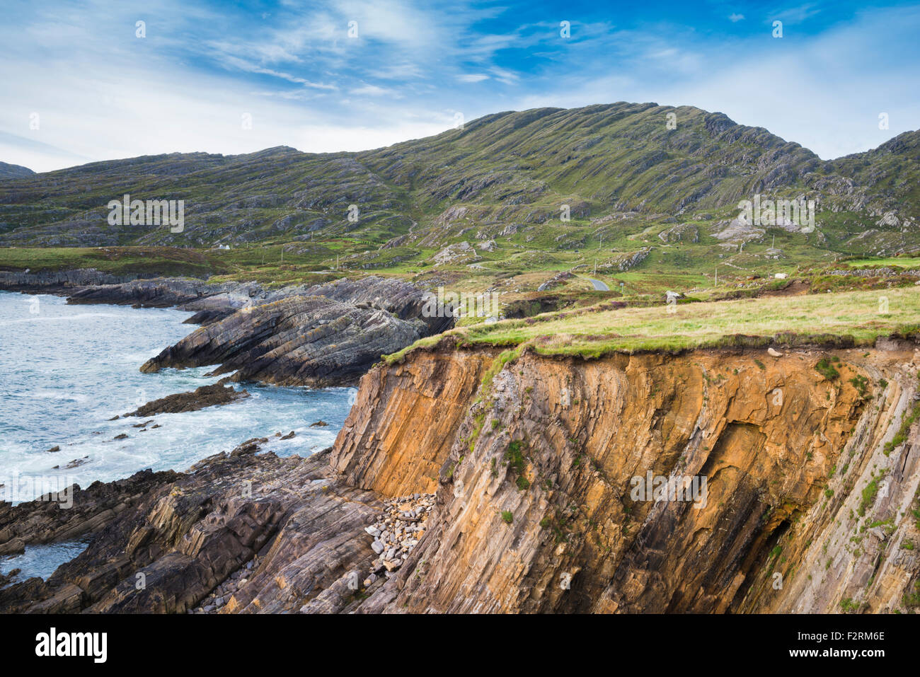 Rocky sea cliffs near Allihies, Beara, County Cork, Ireland, with the Slieve Miskish Mountains in the background Stock Photo