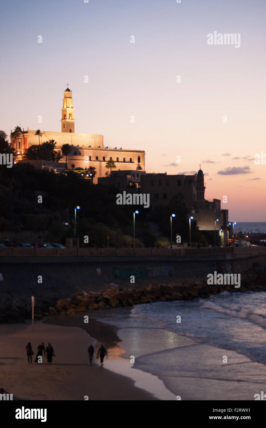Summer day, people, sunset, beach, tower bell of Saint Peter Church and the Great Mosque, Jaffa, Yafo, Yaffo, Tel Aviv, Israel Stock Photo