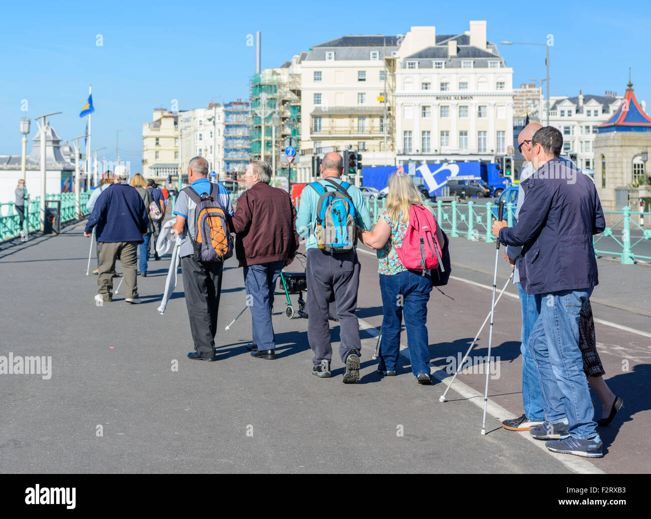 A group of blind people with sticks walking along a seaside promenade in Brighton, East Sussex, England, UK. Stock Photo