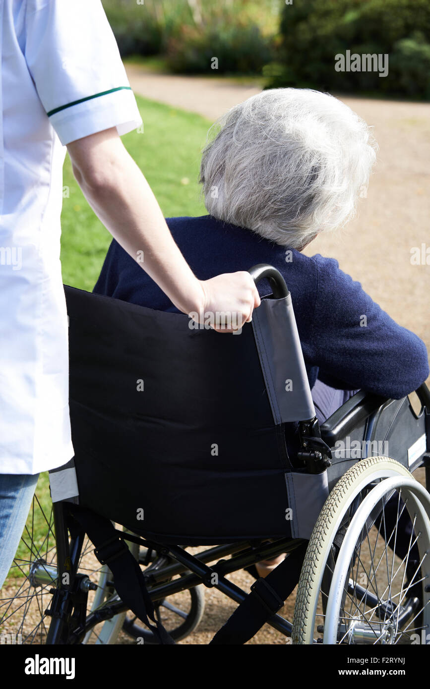 Close Up Of Carer Pushing Senior Woman In Wheelchair Stock Photo