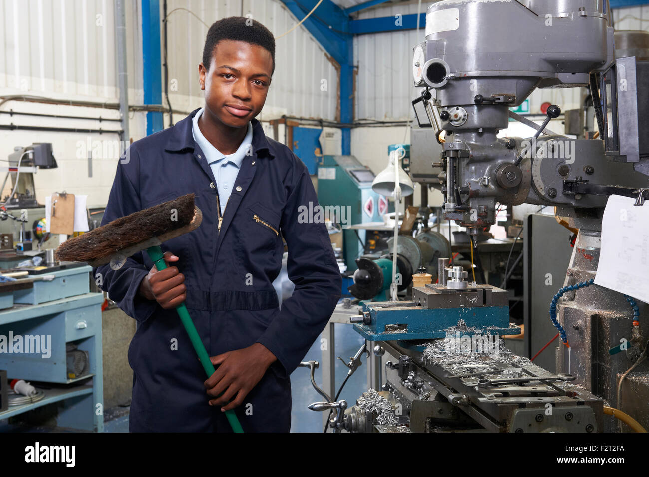 Apprentice In Engineering Factory Sweeping Floor Stock Photo