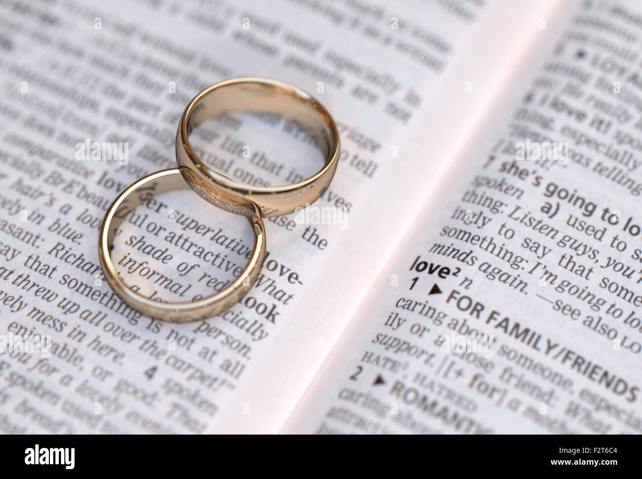 Wedding rings on a dictionary page showing love definition, close up