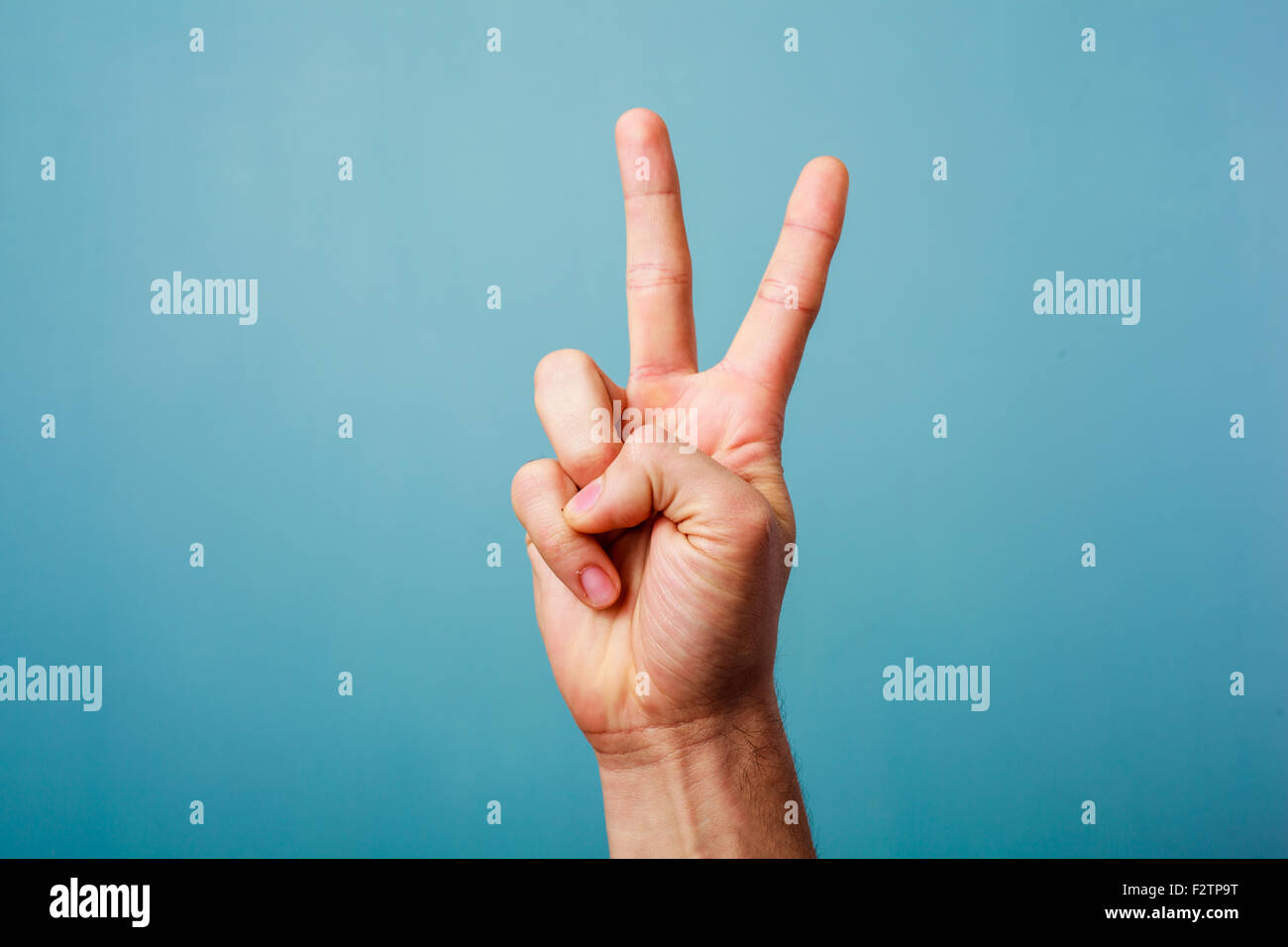Hand gesturing victory on a blue background Stock Photo