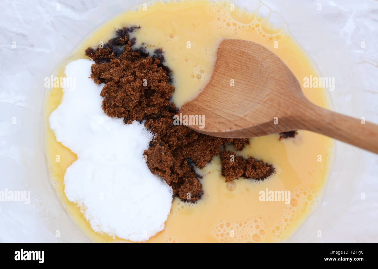 Closeup mixing muscovado sugar and caster sugar into beaten eggs for